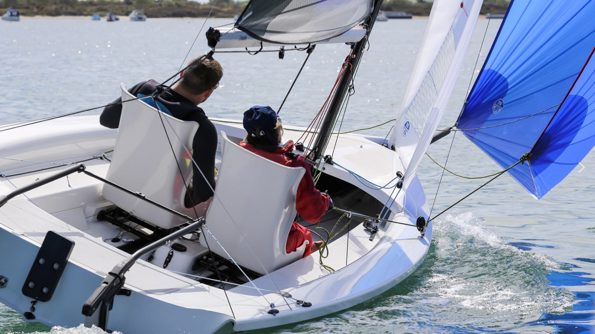 RS Venture Connect für Inklusionssegeln: Behinderter mit Coach, jeweils in einem Schalensitz, im RS Venture segelnd bei Schräglage unter Gennaker