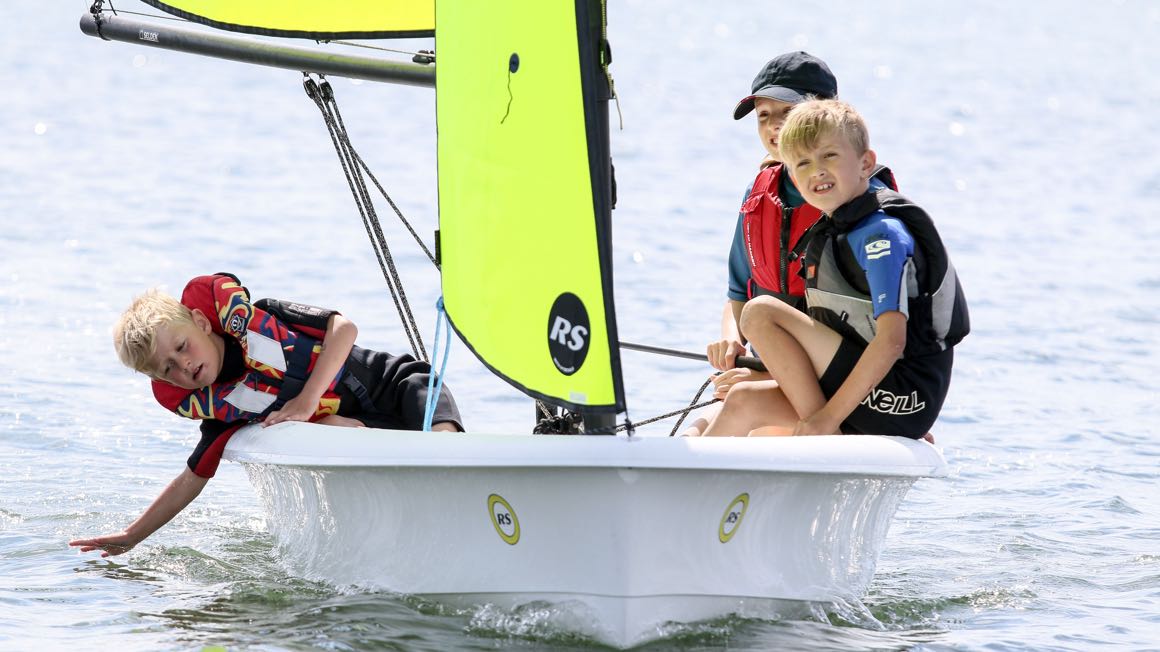 Kinder segeln zu dritt eine RS Zest Segeljolle bei Leichtwind