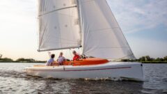 Drei Erwachsene segeln den Daysailor RS Aira 22 und passieren auf einem Kreuzschlag.