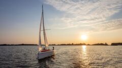 RS Aira 22 segelt von der untergehenden Sonne weg in Richtung des Betrachters an der Kreuz bei leichtem Wind.