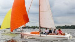 Vier Erwachsene machen gute Fahrt bei Mittelwind unter Gennaker mit ihrer RS Aira 22 - entspanntes Segeln mit großer Bugwelle.